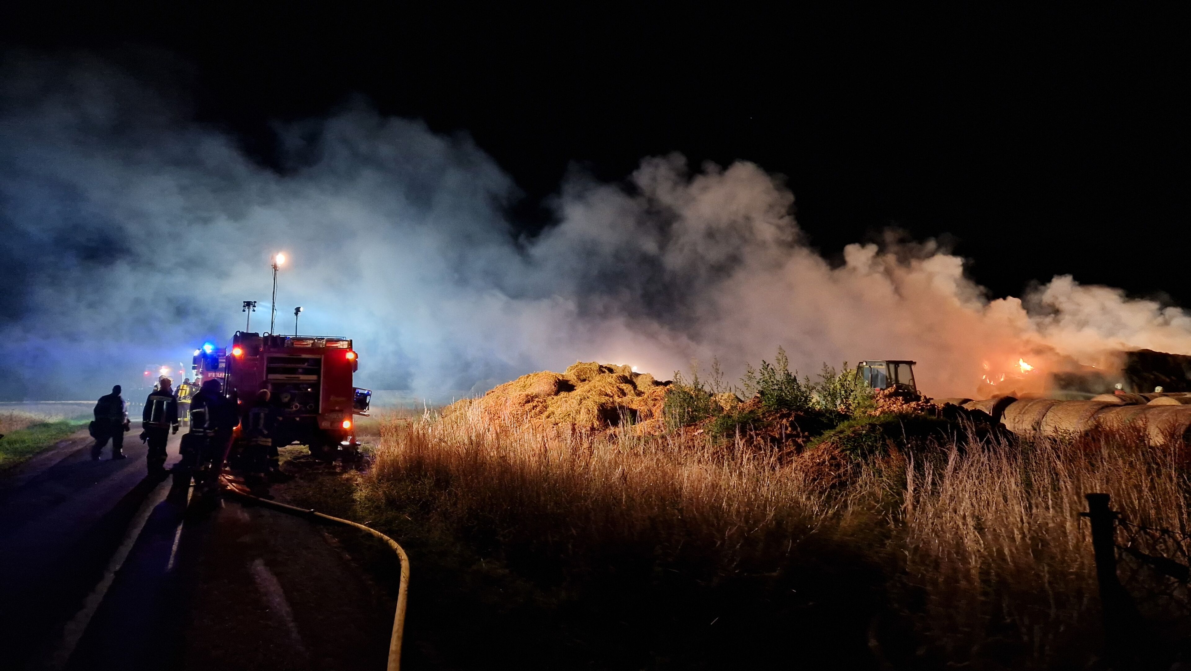 Brennende Heuballen, ausgeleuchtet durch Feuerwehr