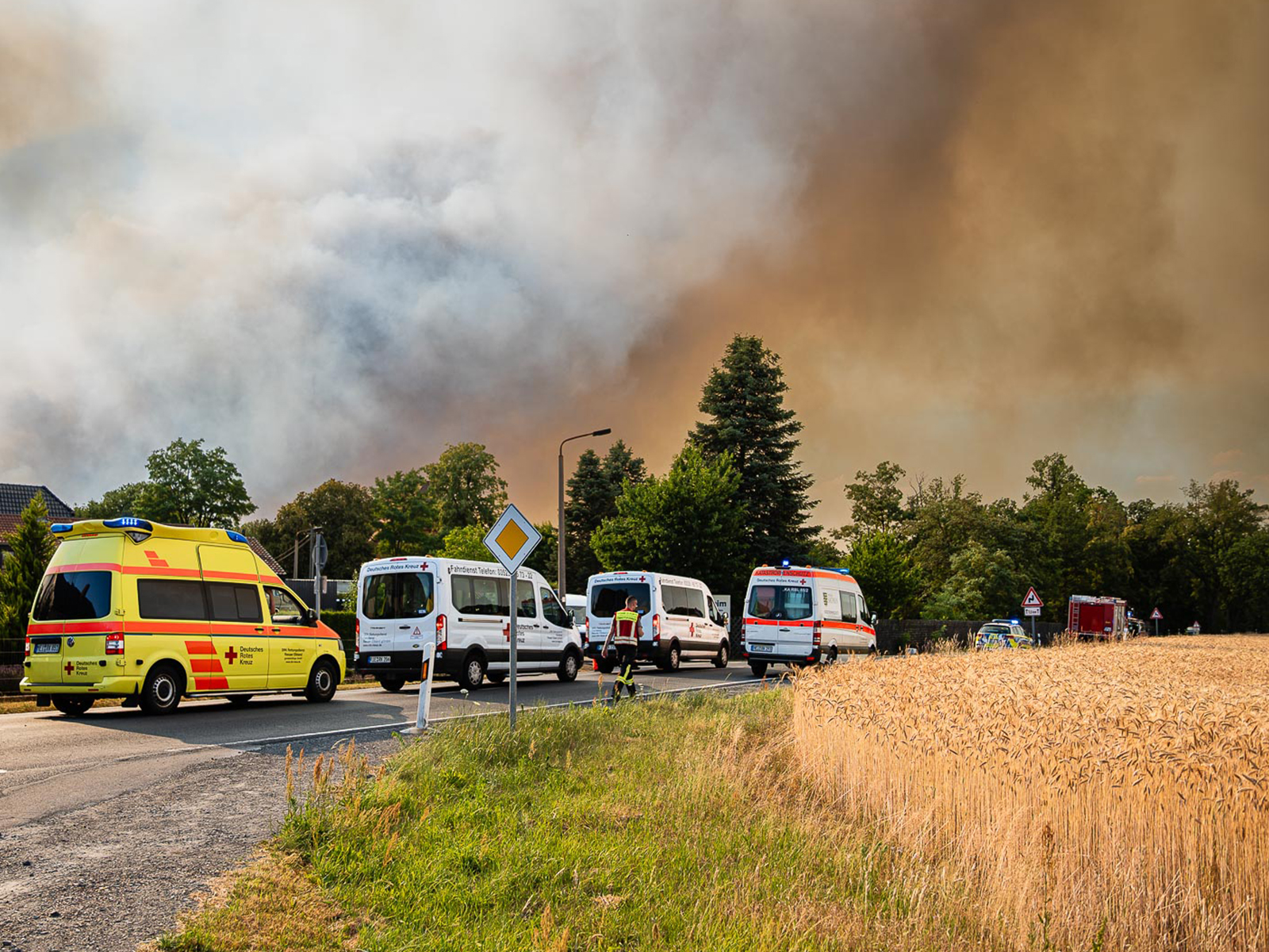 DRK-Einsatzfahrzeuge vor Rauchwolken über Wald