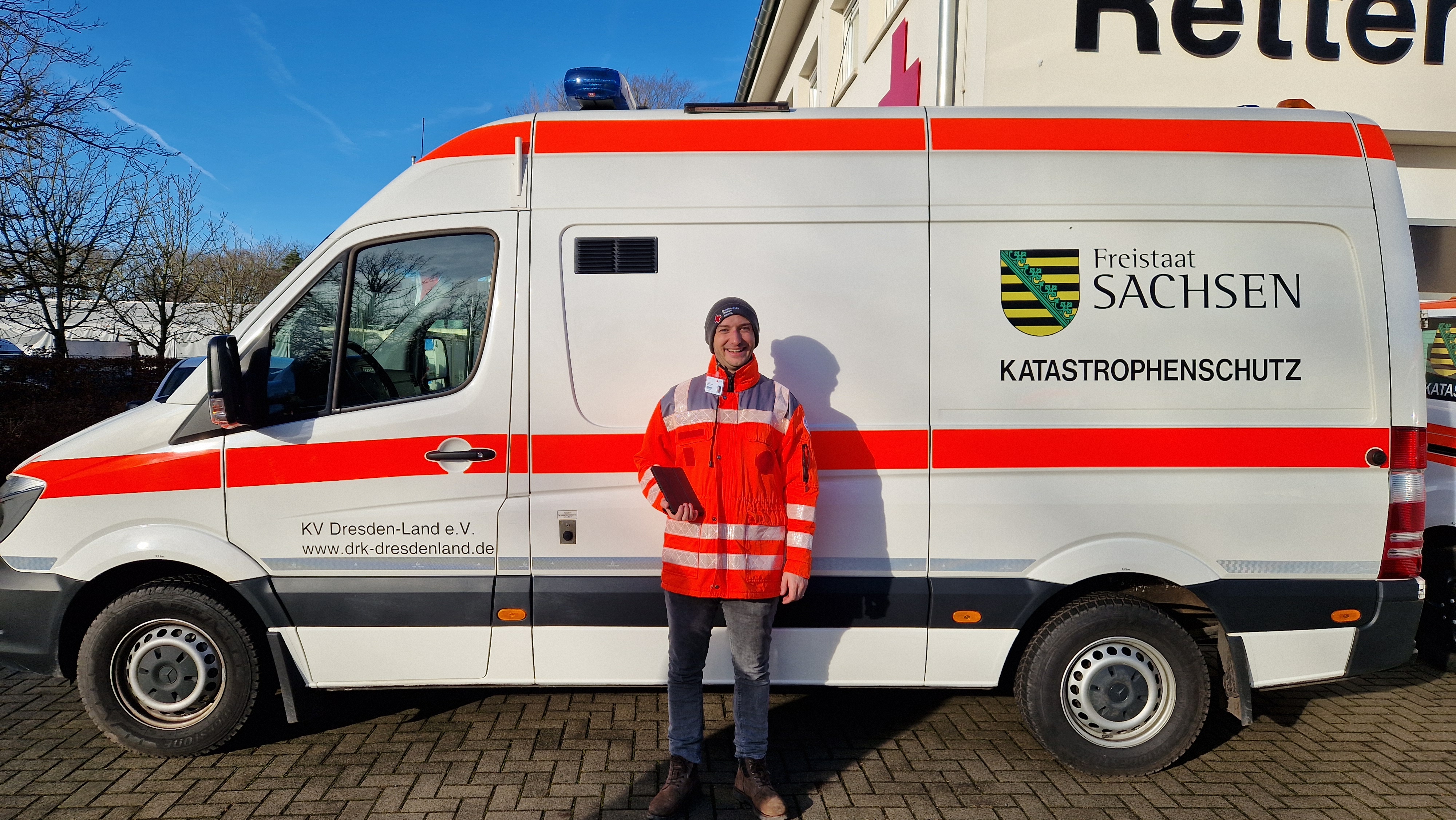 Mitglieder-Werber mit Rotkreuz-Jacke vor einem Einsatzfahrzeug