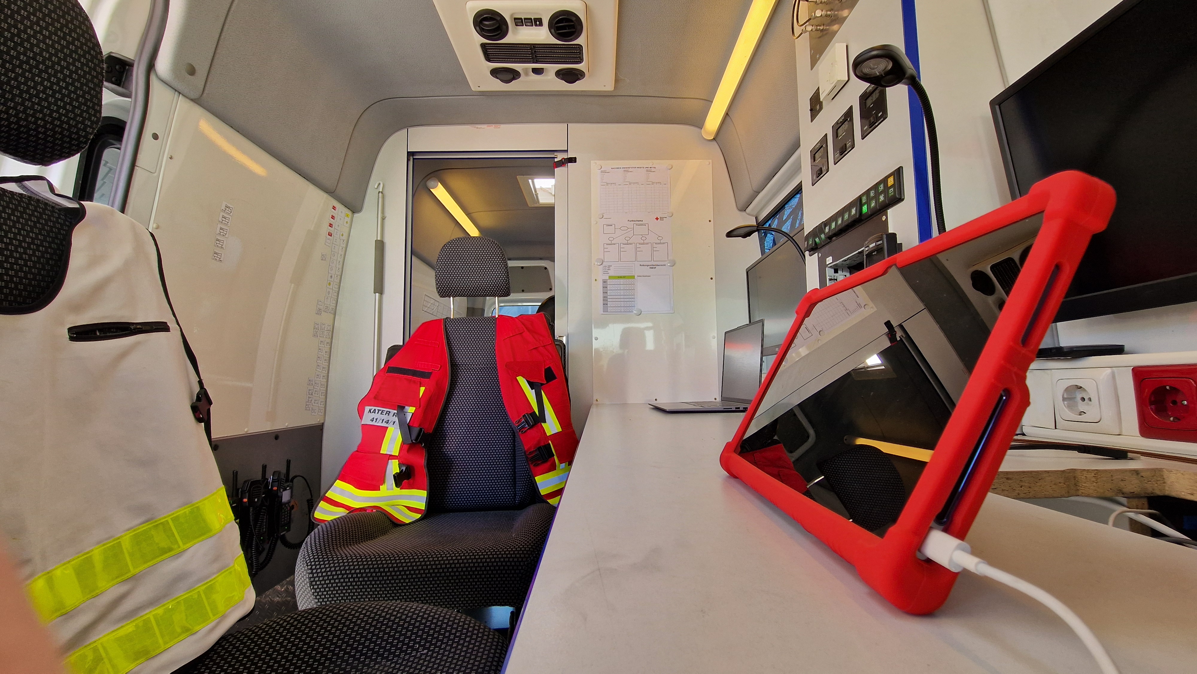 Funkraum mit zwei Sitzplätzen, Tisch, Monitoren, Tablet und Laptop