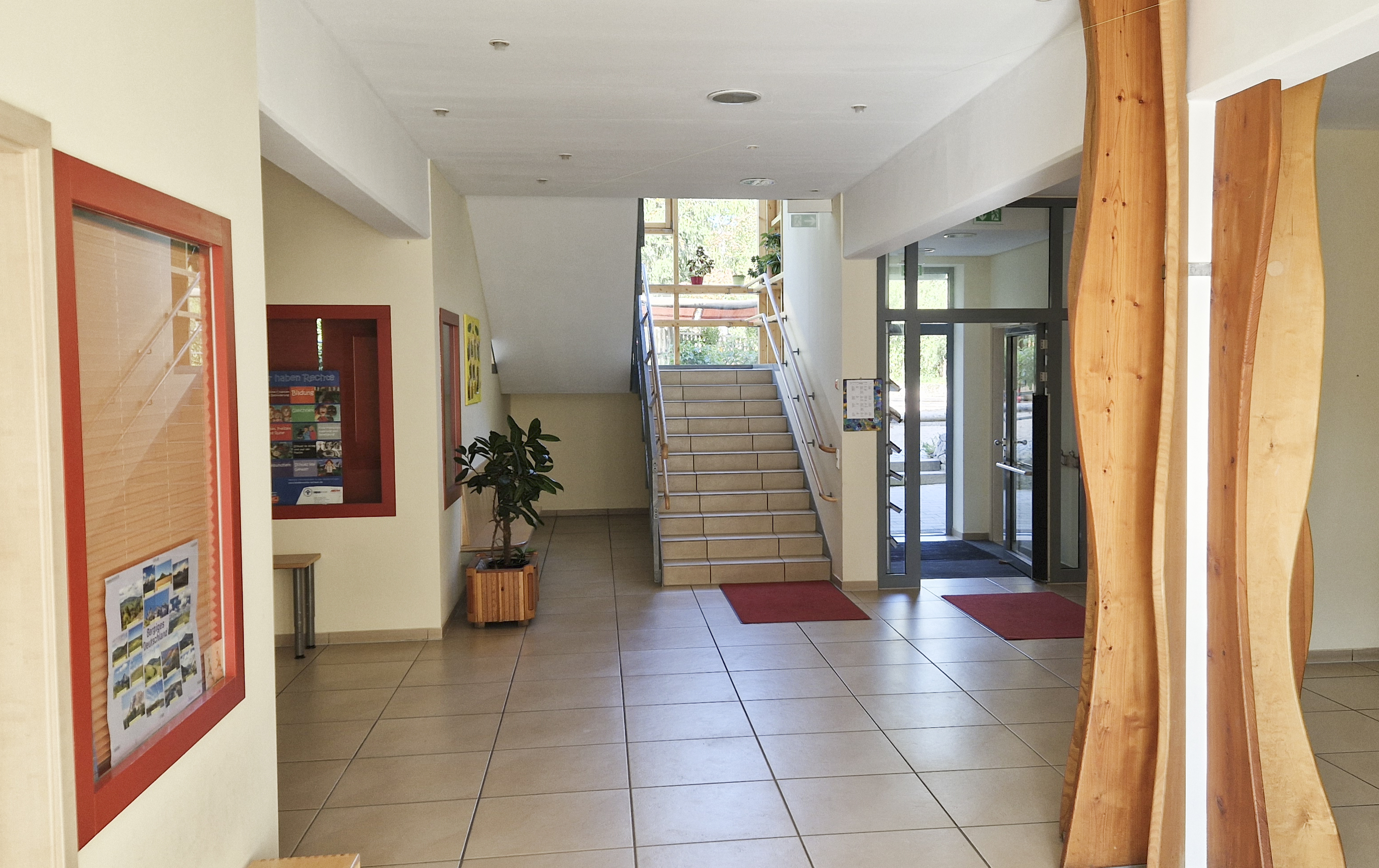 Foyer der Kita mit Infotafel, Treppe, holzverkleideter Ständer