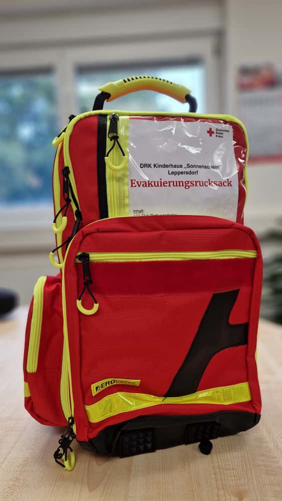 Roter Rucksack mit Aufschrift "Evakuierungsrucksack Kinderhaus Sonnenschein"