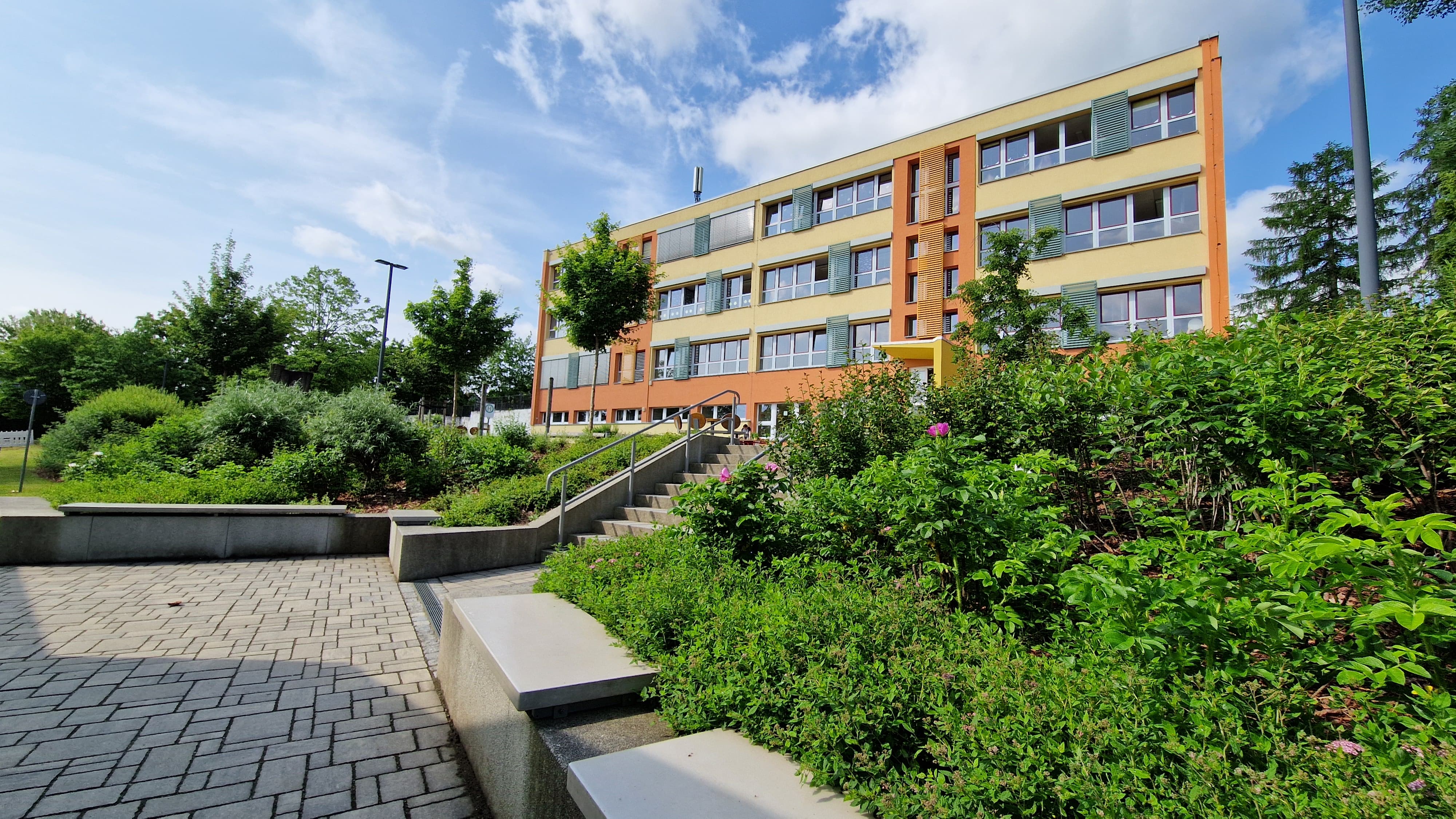 Schulgebäude mit grünen Büschen