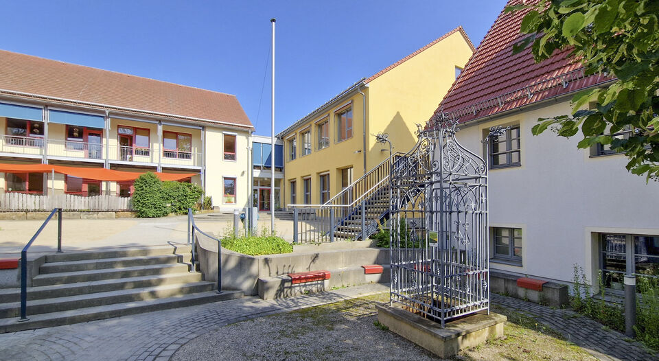 Vorplatz mit Brunnen und Treppe, im Hintergrund Gebäude der Kita